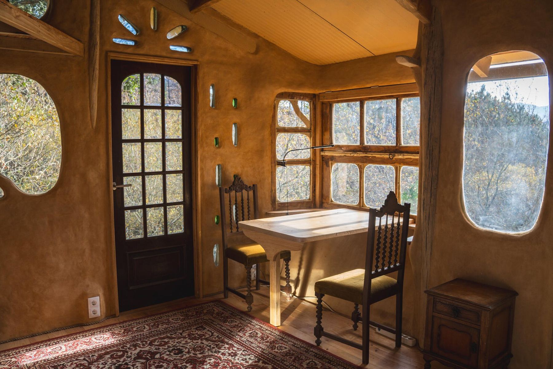 Inside the Clayhouse: clay walls with glass inlays, a desk in the corner window