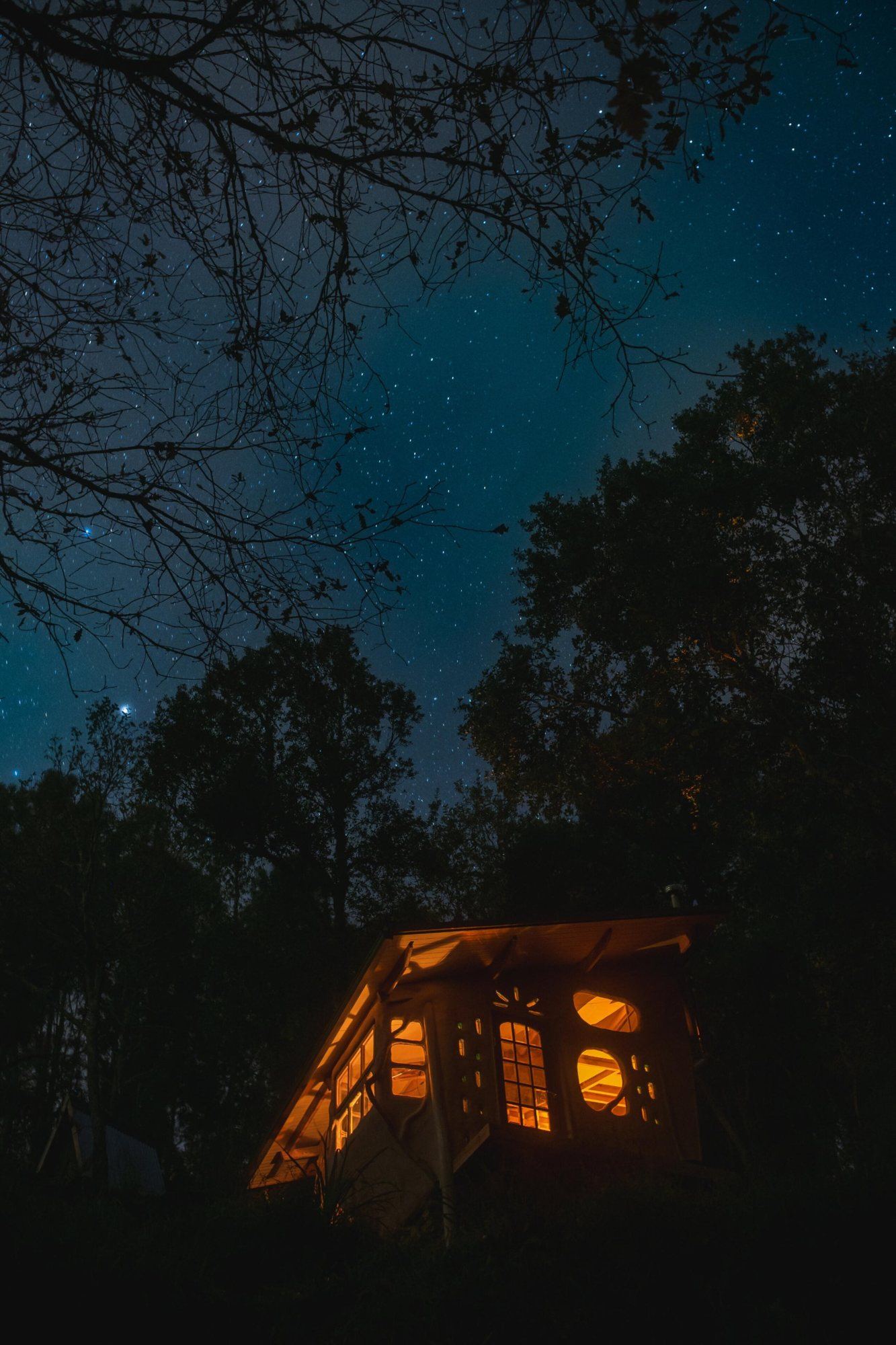 The Clayhouse glowing from inside under a starry winter sky