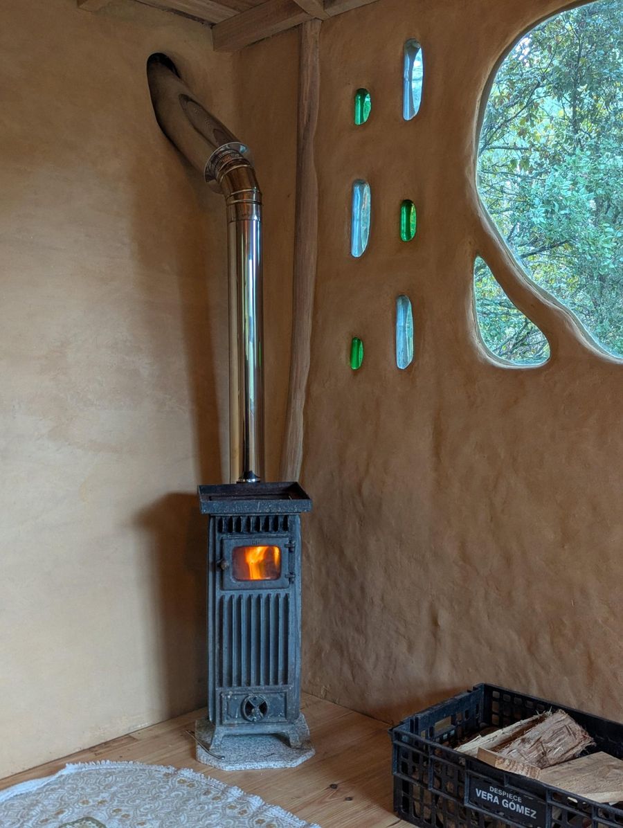 The Clayhouse's small cast-iron wood stove with a fire lit