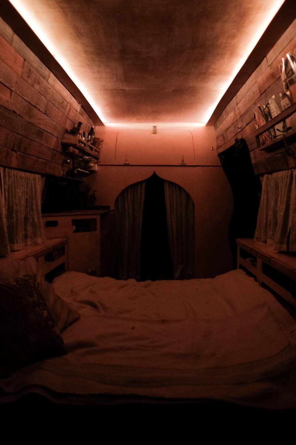 Inside the van: a bed under warm timber walls